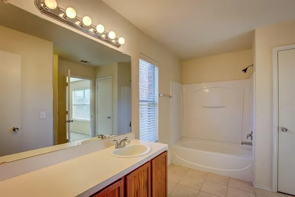 a bathroom with a tub a sink and a large mirror