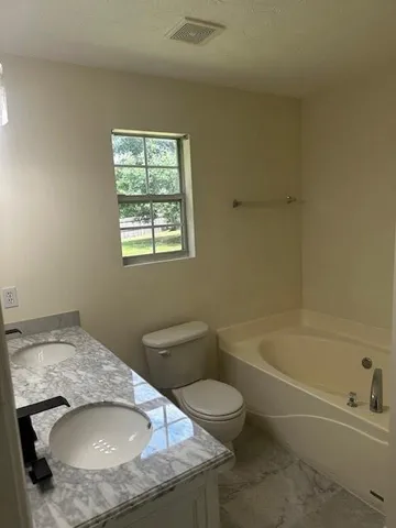 a bathroom with a granite countertop sink a toilet and bathtub