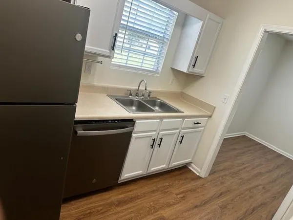 a kitchen with stainless steel appliances white cabinets and a wooden floor