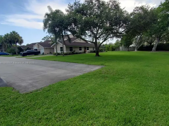 a view of a house with a big yard and large trees