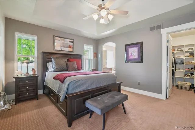 a spacious bedroom with a bed a dresser and paintings on the wall