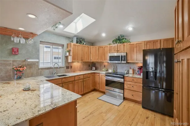 a kitchen with granite countertop a refrigerator stove top oven and sink