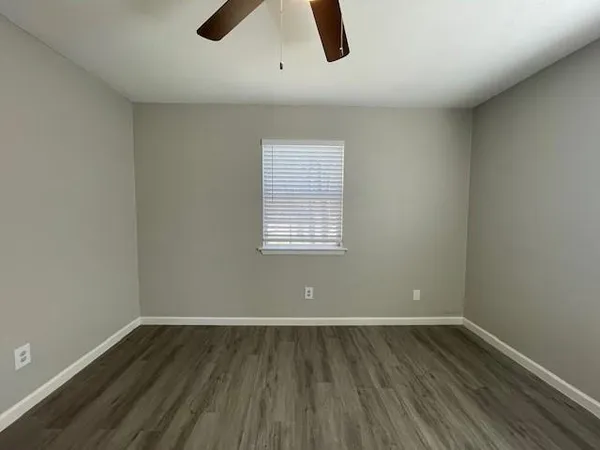 an empty room with ceiling fan and window