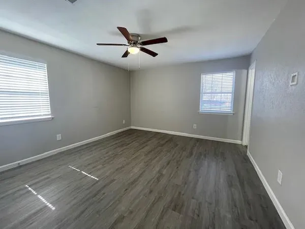 a view of an empty room with wooden floor and a window