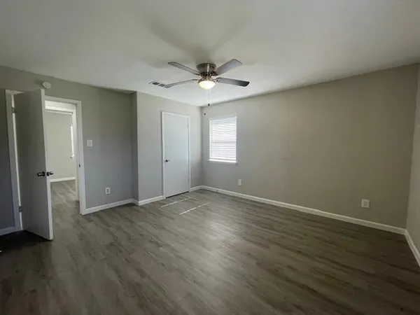 an empty room with wooden floor and windows