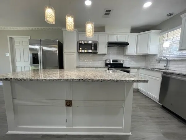 a kitchen with stainless steel appliances granite countertop a sink stove and cabinets