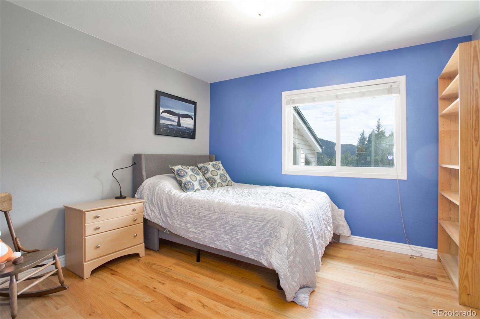 12079 Tecumseh Trail Conifer, CO 80433 - Photo 24 of 38 a bedroom with a bed and wooden floor