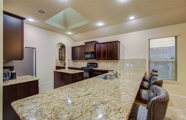a kitchen with stainless steel appliances granite countertop sink stove top oven and cabinets