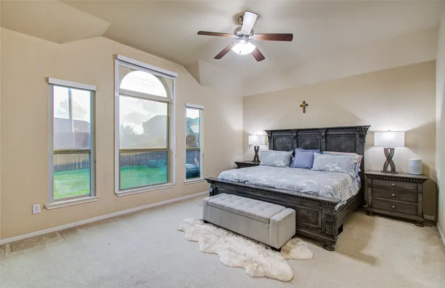 a spacious bedroom with a bed painting on wall and a large window