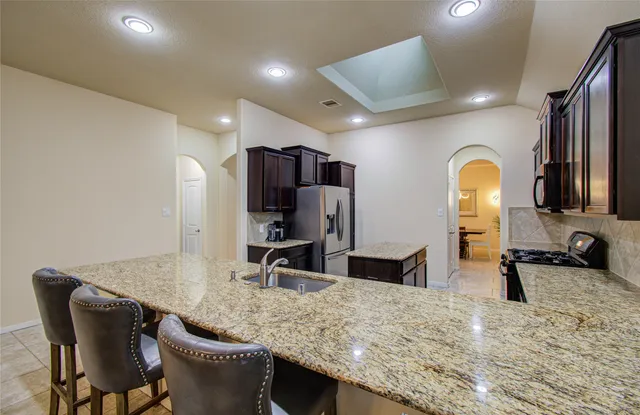 a kitchen with stainless steel appliances granite countertop a sink a stove and refrigerator