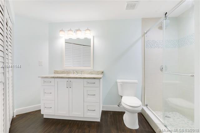 100 Uno Lago Drive, Unit 205 Juno Beach, FL 33408 - Photo 10 of 13 a bathroom with a granite countertop toilet a sink and a shower