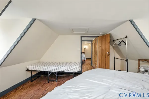 a view of a hallway with wooden floor and a bathroom