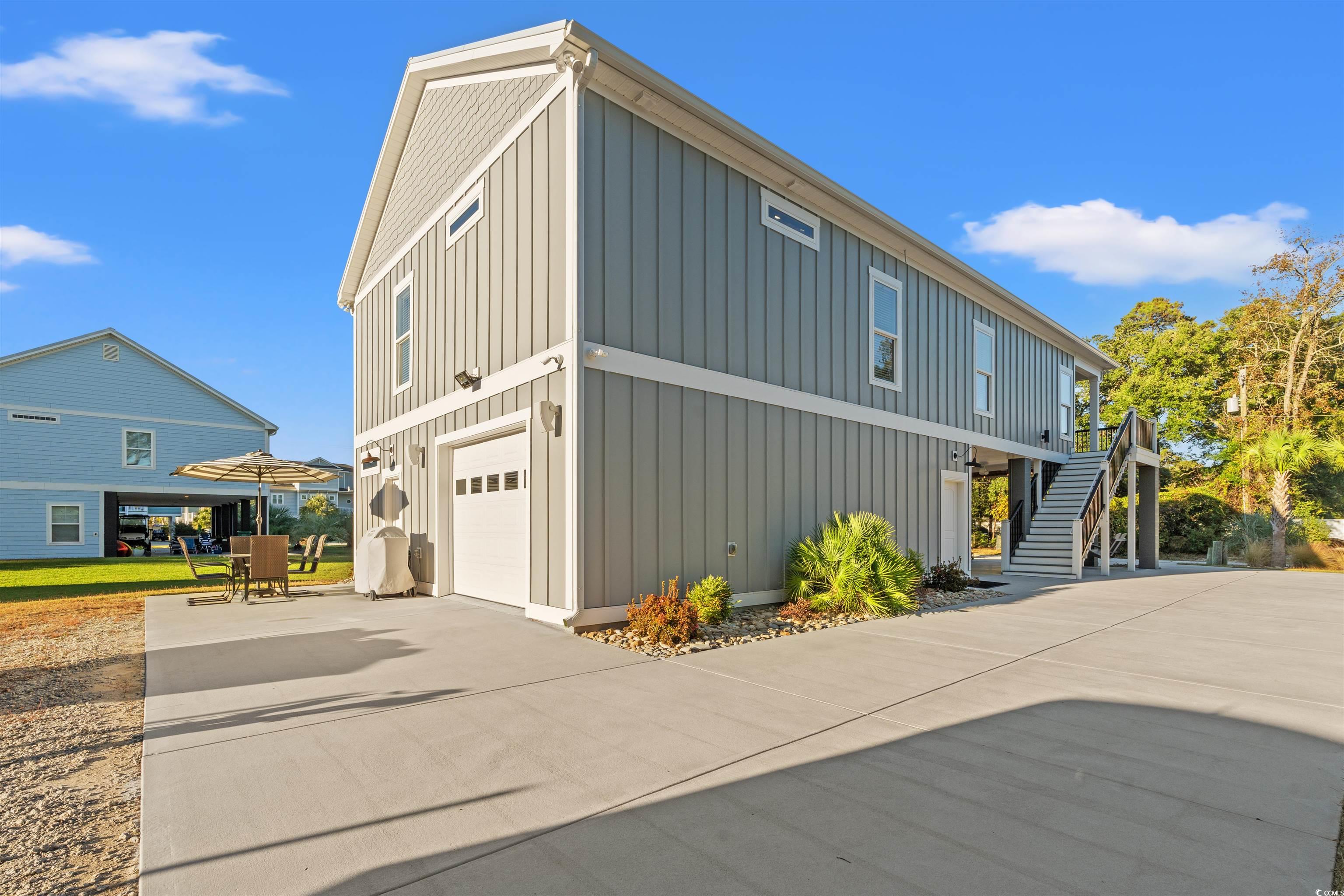 355 Oak Avenue Murrells Inlet, SC 29576 - Photo 4 of 34 View of property exterior with board and batten siding, an attached garage, stairs, and concrete driveway