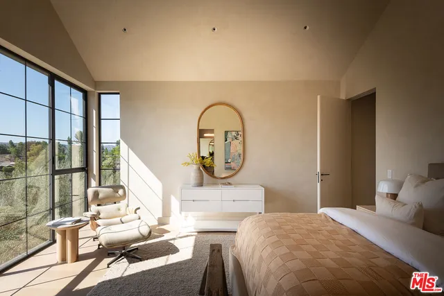 a bedroom with a bed a mirror and next to a window