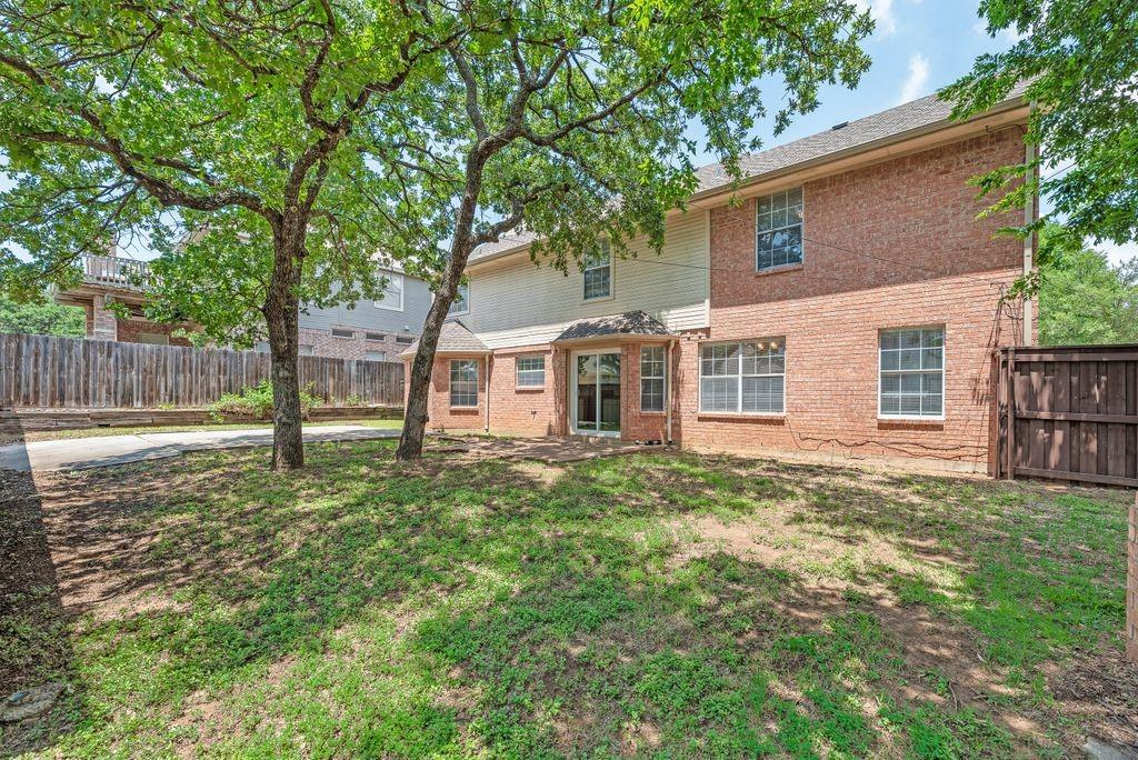 5610 Eagle Rock Road Arlington, TX 76017 - Photo 33 of 33 Private backyard featuring mature trees, a brick exterior, multiple windows, and a sliding glass door