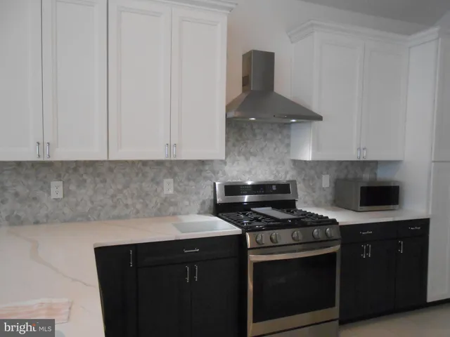a kitchen with stainless steel appliances a stove and a white cabinets