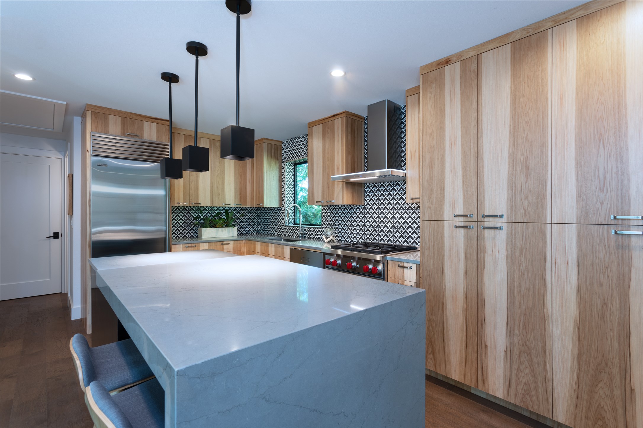 700 Jessie Street Austin, TX 78704 - Photo 25 of 40 ADU kitchen featuring a kitchen island, light stone counters, premium appliances, light wood finish cabinetry, and dark wood-style flooring