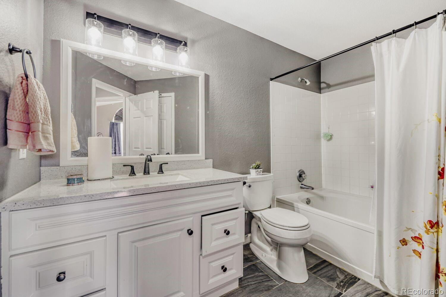 10371 Cook Way, Unit 107 Thornton, CO 80229 - Photo 10 of 34 a bathroom with a granite countertop sink a toilet and a mirror