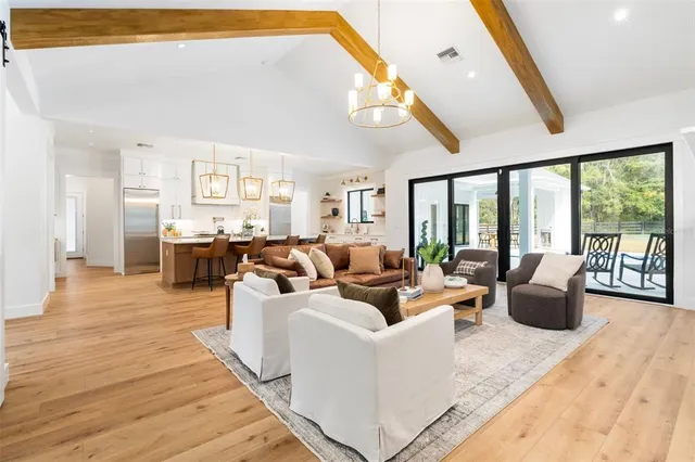 a kitchen with stainless steel appliances granite countertop a refrigerator a sink dishwasher a stove and white cabinets with wooden floor