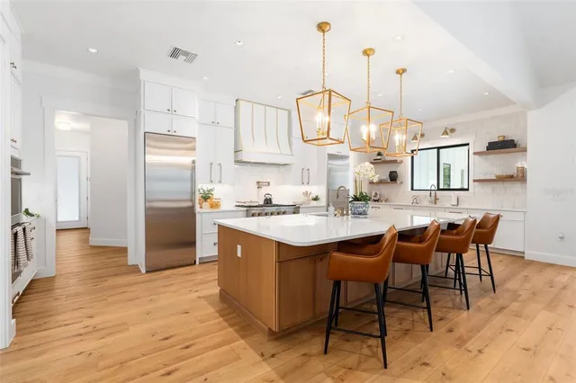 a large kitchen with stainless steel appliances granite countertop a sink a stove and a refrigerator