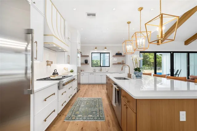 a large kitchen with stainless steel appliances a large counter top a stove and a sink