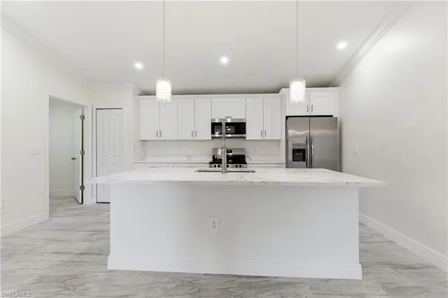 a large kitchen with stainless steel appliances a refrigerator a stove a sink a microwave and white cabinets