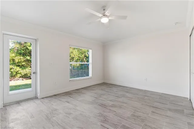 an empty room with wooden floor ceiling fan with window