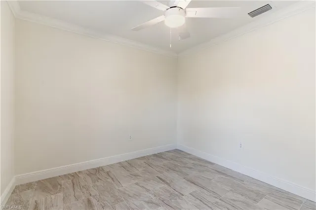 an empty room with a window and chandelier fan
