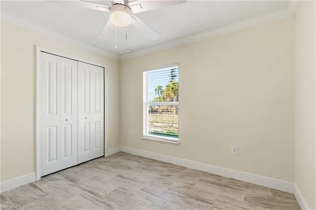 an empty room with chandelier fan and windows
