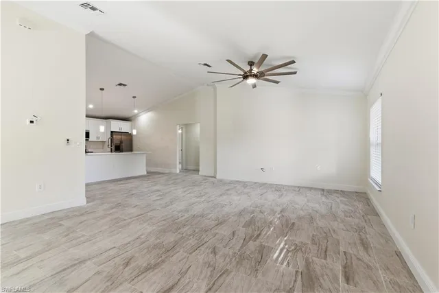 a view of a big room with wooden floor a ceiling fan and windows