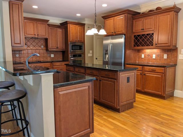 a kitchen with stainless steel appliances granite countertop a refrigerator a stove and a sink