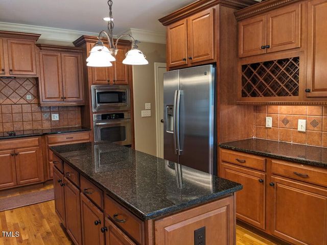 a kitchen with stainless steel appliances granite countertop a sink a microwave and a refrigerator