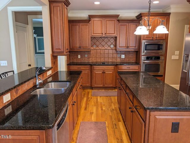 a kitchen with kitchen island granite countertop a sink appliances and cabinets