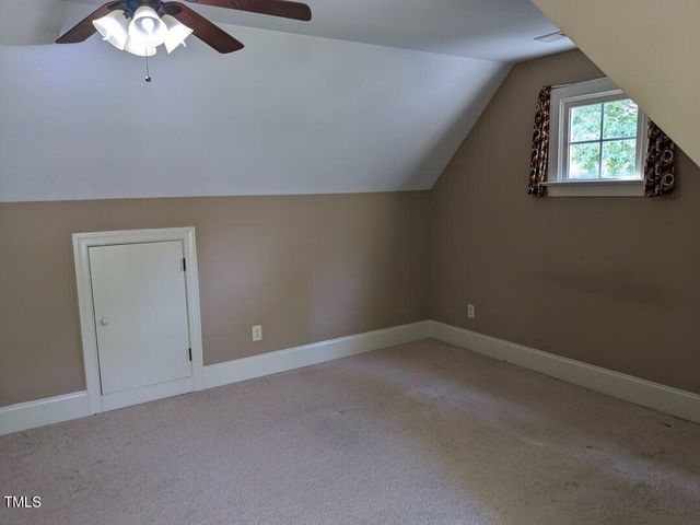 an empty room with a chandelier fan and windows