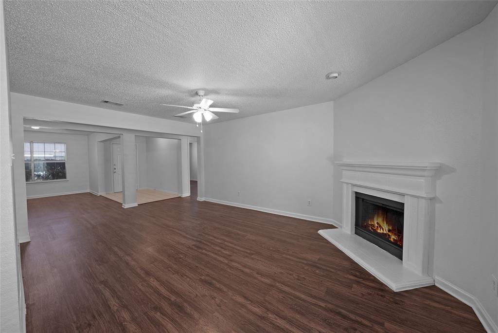 2910 Chisholm Trail Corinth, TX 76210 - Photo 6 of 30 a view of an empty room with wooden floor fireplace and a window
