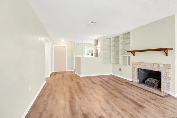 a view of empty room with wooden floor and fireplace