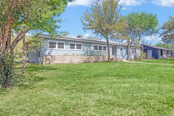 a front view of a house with a garden and trees
