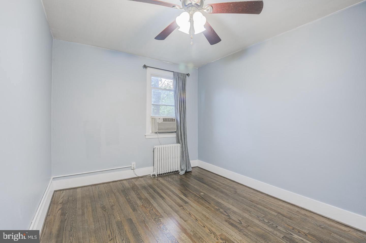 1106 Meridene Drive Baltimore, MD 21239 - Photo 5 of 9 an empty room with wooden floor chandelier fan and windows