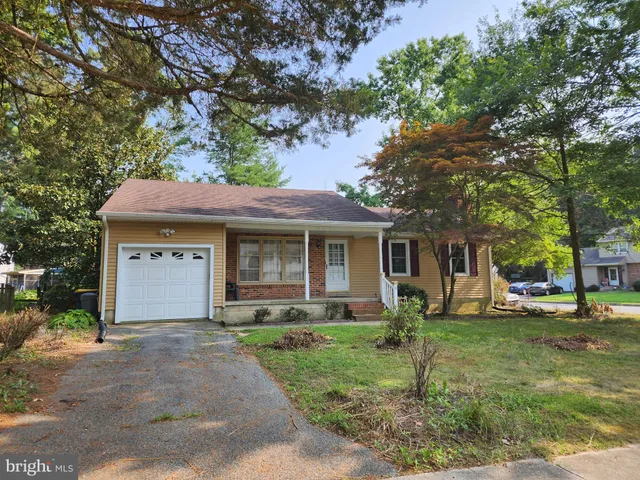a front view of a house with garden and trees