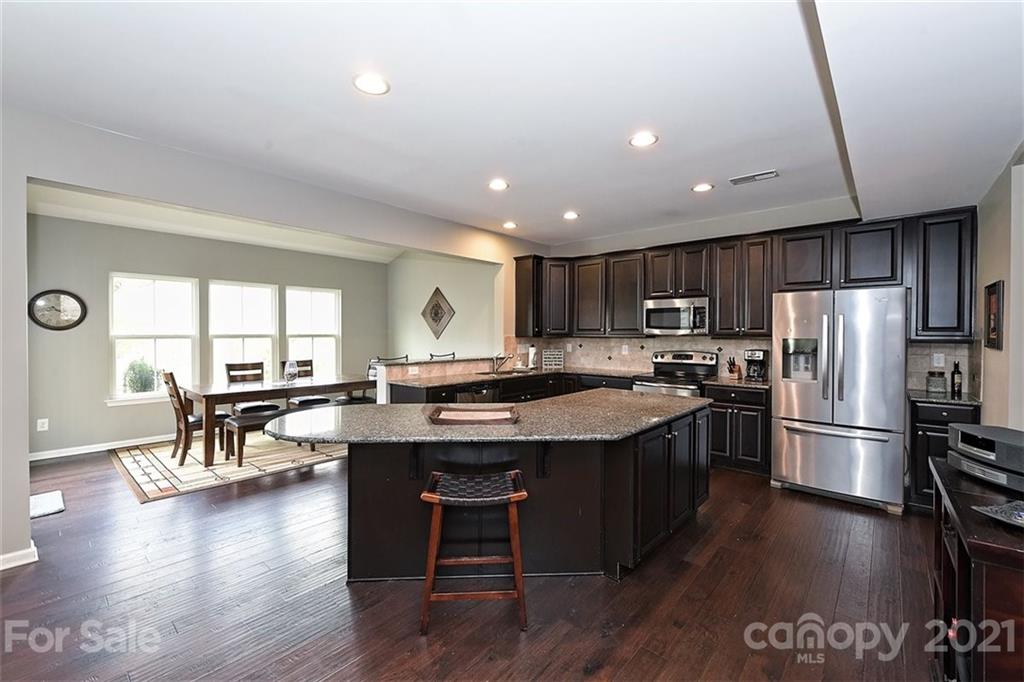 3006 Fallondale Road Waxhaw, NC 28173 - Photo 19 of 48 a kitchen with stainless steel appliances granite countertop a stove a refrigerator a sink a dining table and chairs with wooden floor