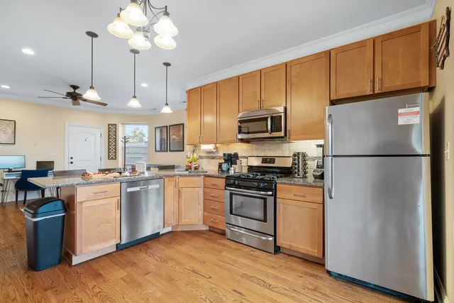 a kitchen with stainless steel appliances granite countertop a refrigerator a stove a sink dishwasher and a refrigerator with wooden floor