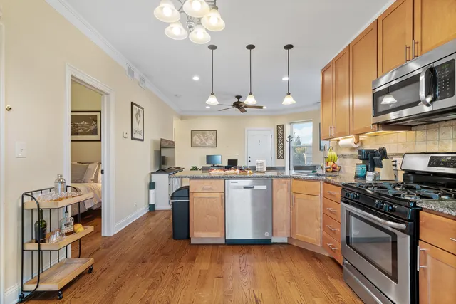 a kitchen with stainless steel appliances granite countertop a stove top oven a refrigerator a sink dishwasher and white cabinets with wooden floor