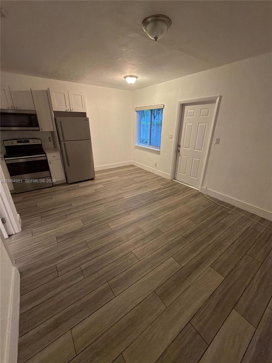 1145 Northwest 3rd Street, Unit 3 Miami, FL 33128 - Photo 2 of 8 a view of an empty room with wooden floor and a window