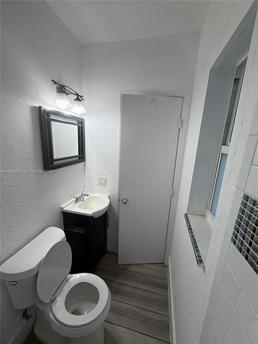1145 Northwest 3rd Street, Unit 3 Miami, FL 33128 - Photo 5 of 8 a bathroom with a toilet a sink and mirror