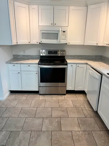 a kitchen with white cabinets a refrigerator and a sink