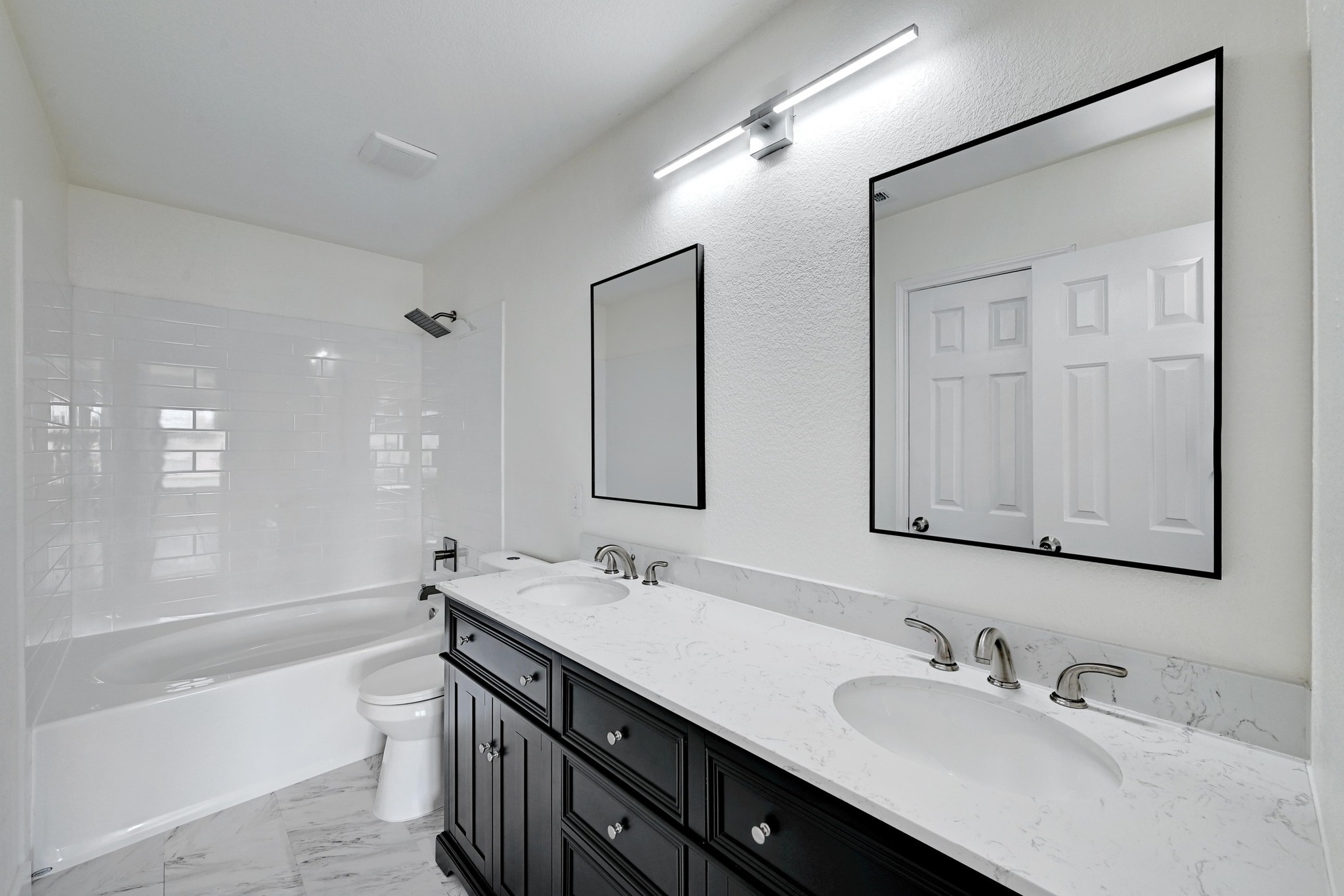 7413 L Marble Ridge Drive Austin, TX 78747 - Photo 15 of 30 Dual vanity featuring a white countertop with integrated sinks, black cabinetry, and rectangular framed mirrors