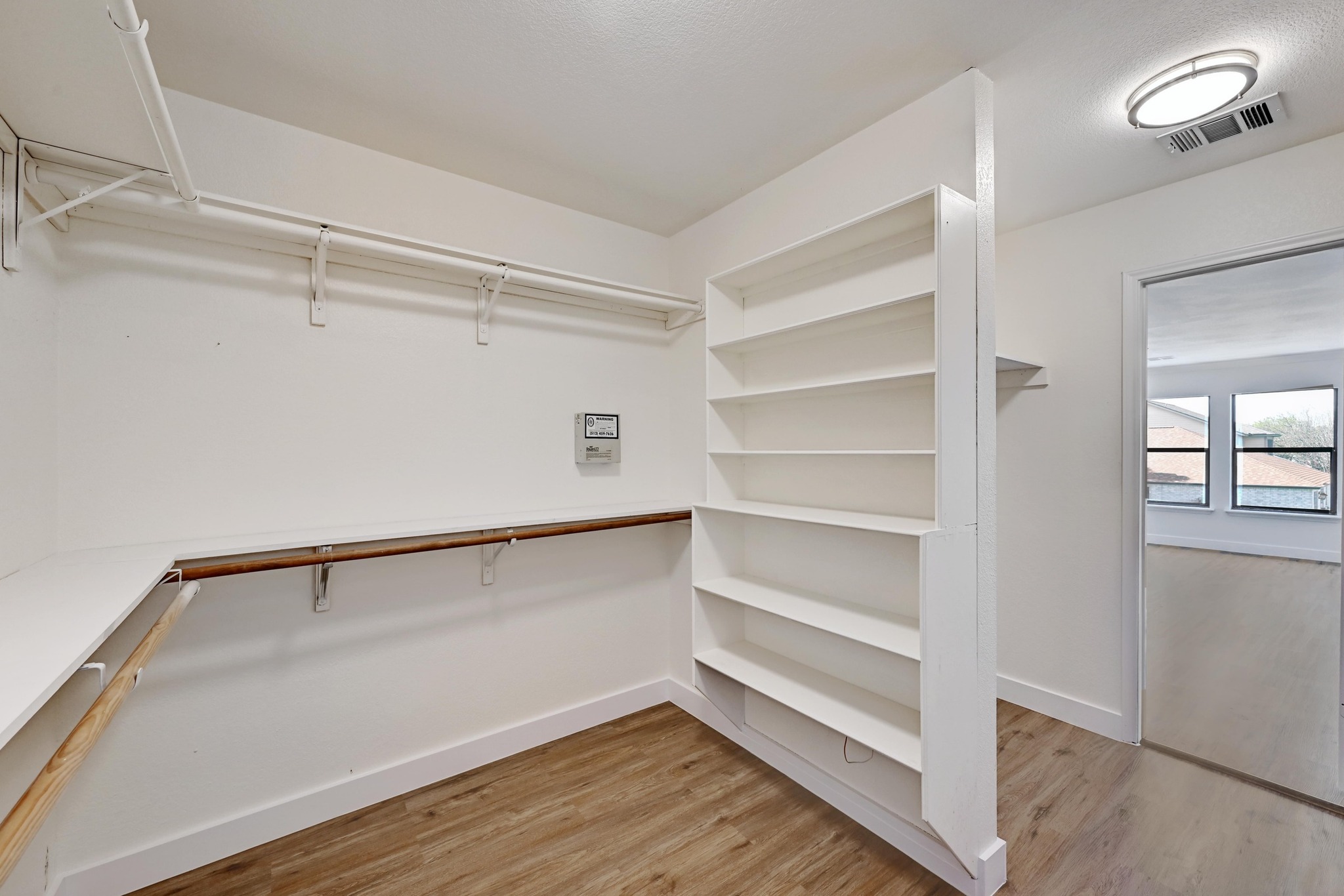 7413 L Marble Ridge Drive Austin, TX 78747 - Photo 16 of 30 Walk-in closet featuring built-in shelving, two levels of hanging rods, corner shelving, wood-finish flooring, and a flush-mount ceiling light