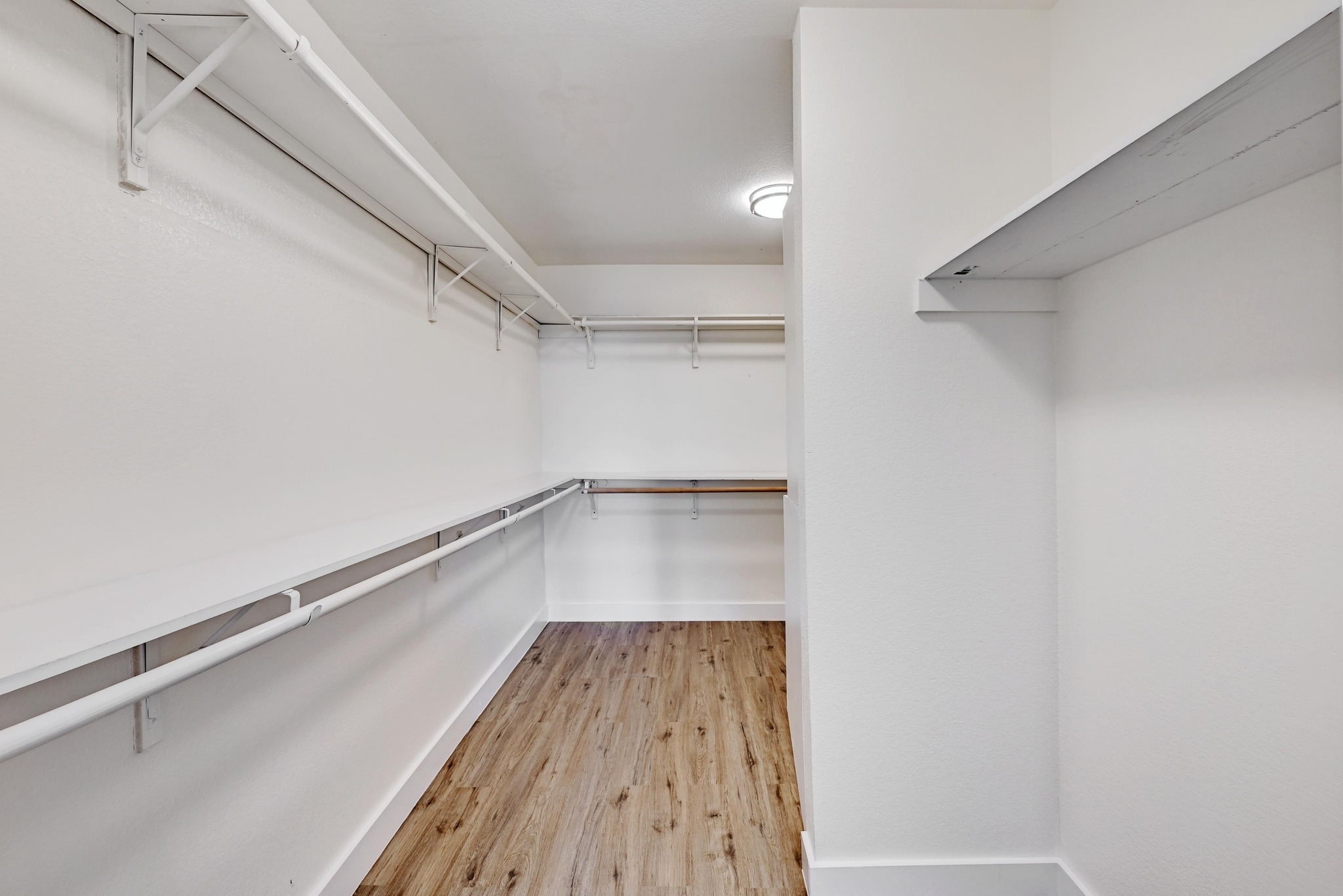 7413 L Marble Ridge Drive Austin, TX 78747 - Photo 17 of 30 Walk-in closet featuring wood-finish flooring, recessed lighting, and extensive built-in shelving and hanging rods
