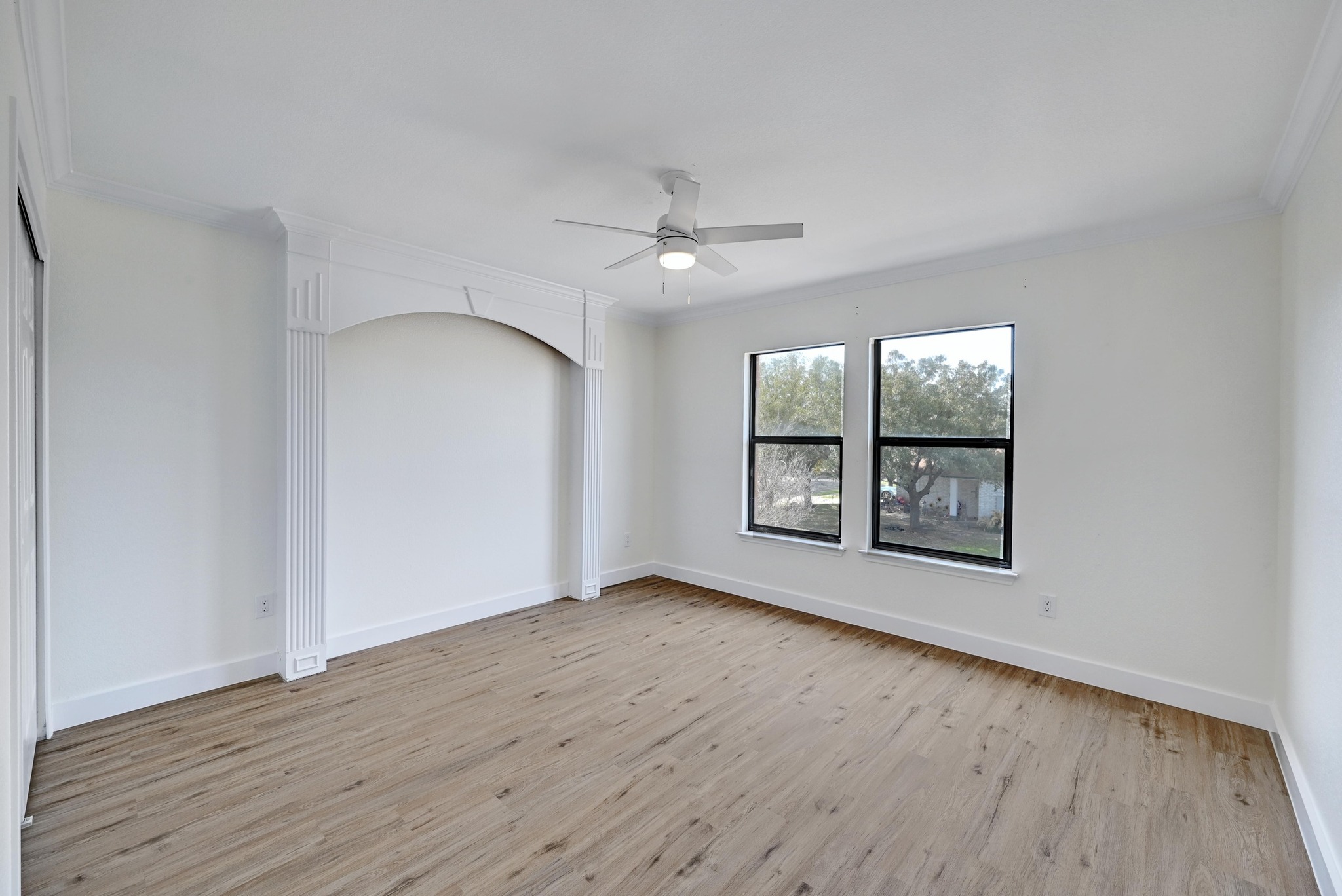 7413 L Marble Ridge Drive Austin, TX 78747 - Photo 19 of 30 Spacious room featuring wood-finish flooring, two large windows, a decorative arched alcove, and a ceiling fan with integrated lighting