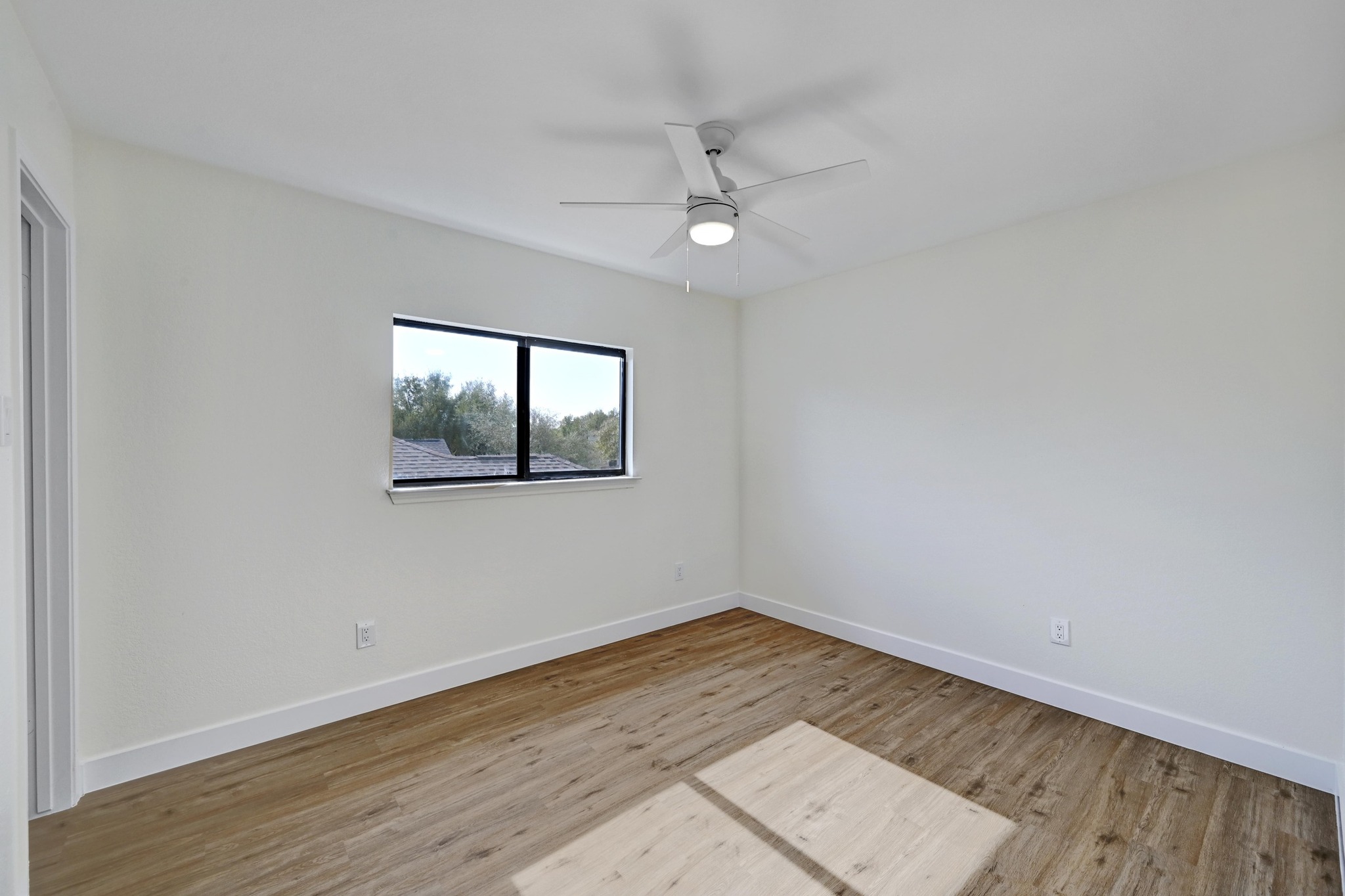 7413 L Marble Ridge Drive Austin, TX 78747 - Photo 20 of 30 Bright room featuring wood-finish flooring, a white ceiling fan with integrated lighting, and a black-framed window